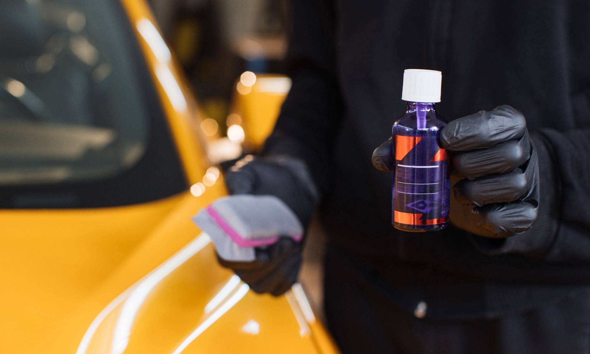 Bravus detailer holding ceramic coating product next to vehicle