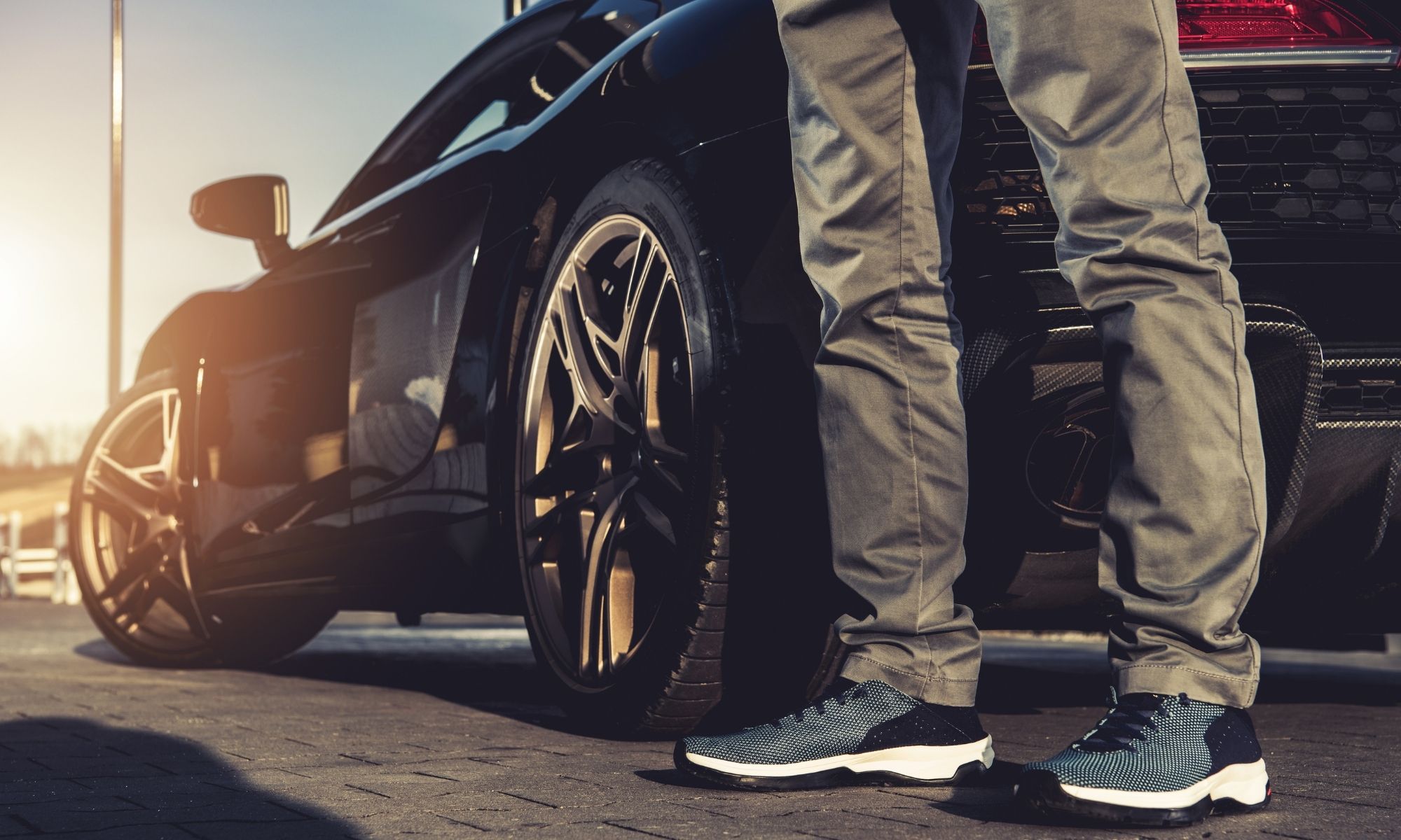 Black sports car with gold wheels at sunset